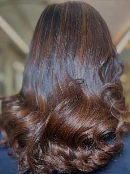 A beautiful result of a color and styling session. The deep brunette base is enhanced with subtle caramel highlights and finished with glamorous, bouncy curls.
