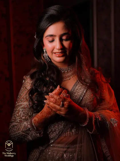 This candid shot captures the bride's radiant smile during her engagement ceremony. The makeup is soft and luminous, designed to catch the light beautifully.