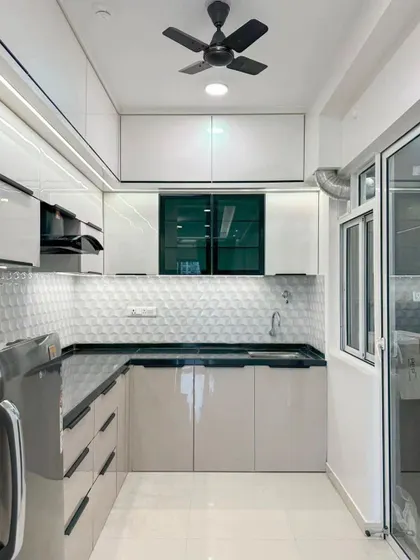 An L-shaped kitchen design featuring beige and white handleless cabinets and a 3D geometric tile backsplash for a modern, textured look.