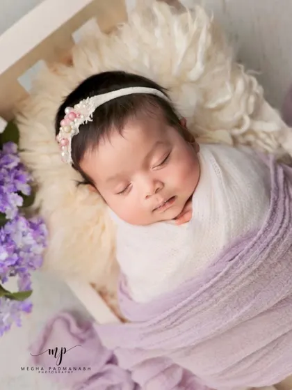 This angle shows the baby nestled in a white miniature bed.