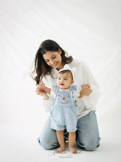 A mother helps her baby take her first wobbly steps. This is a milestone moment, full of love, encouragement, and adorable concentration.