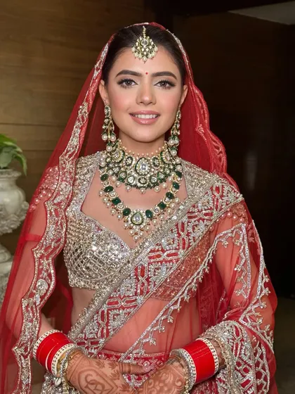 A full portrait of my stunning bride Ritika. The soft glam makeup perfectly balances the heavily embellished red lehenga and emerald jewelry.