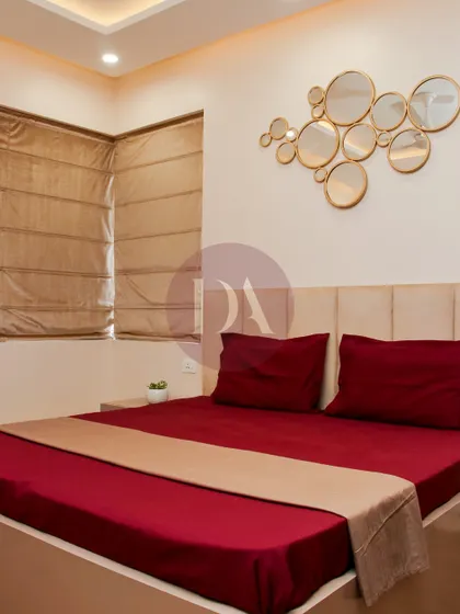 This guest bedroom combines a rich red bedspread with a neutral headboard and a striking gold mirror art piece. The design is simple yet elegant, creating a warm and welcoming space for visitors.