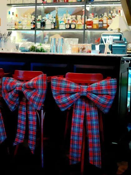 Bar stools decorated with large, festive tartan bows, adding a touch of holiday cheer to the restaurant's decor.
