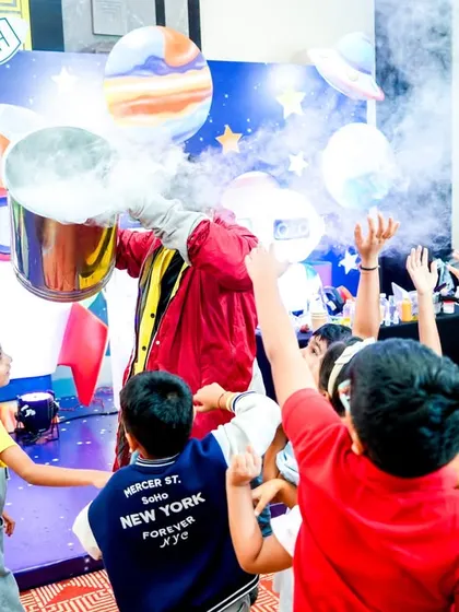 An interactive science show where kids gather around in excitement as the performer creates a cloud of smoke with a safe chemical reaction.