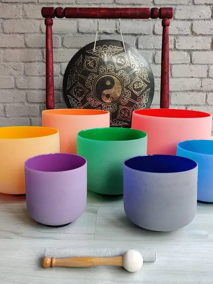 A vibrant set of colored crystal singing bowls and a gong. These instruments are not only beautiful but are also tuned to specific frequencies to aid in chakra healing and emotional balance.
