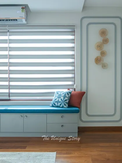 A close-up of the custom window seat, showcasing its functionality with both cabinets and drawers for storage. The zebra blinds offer flexible light control for this comfortable corner.