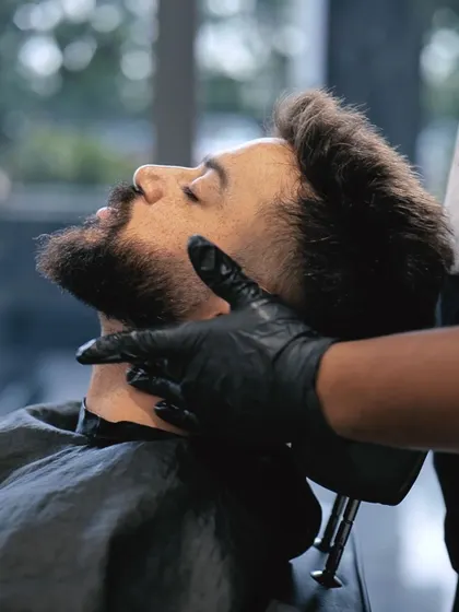 A client relaxing while our expert barber provides a precise beard trim and shaping service.