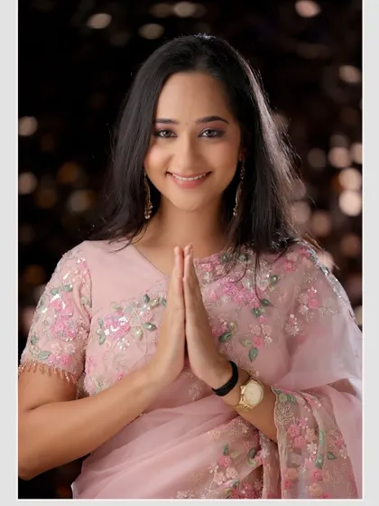 A welcoming and graceful pose in a delicate pink saree. This image radiates warmth and is perfect for festive or family-oriented themes.