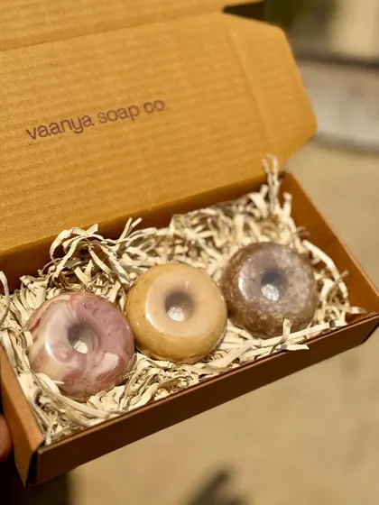 A still shot of our Donut Soap Box, highlighting the different textures and colors of the Sweet Rose, Haldi Doodh, and Vanilla Scrub soaps.