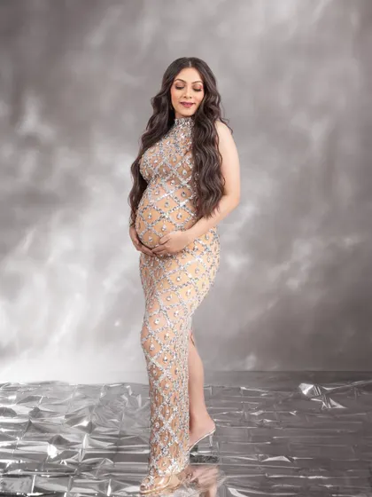 A serene and glowing portrait, with the mom-to-be gently cradling her bump in this dazzling gown.