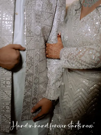 A close-up, detailed shot of the couple's coordinated outfits and the bride's hand on the groom's arm. This photo focuses on the textures and details that make their look unique.