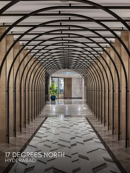 An arched corridor at 17 Degrees North, creating a dramatic and rhythmic procession through the space. The design uses repeating metal arches and patterned marble flooring to guide guests and add a sense of grandeur.