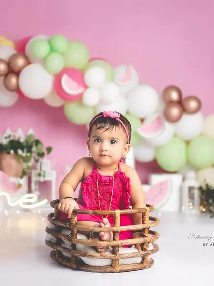 A wide shot of the watermelon-themed first birthday setup, showing the beautiful balloon arch and fun props.
