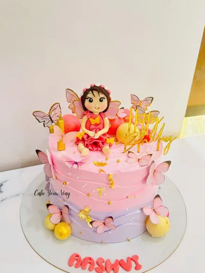 A whimsical fairy cake with pink and purple ombre frosting, decorated with fluttering butterflies.