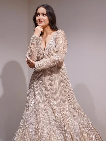 This beige gown with all-over stone work is pure glamour. The long sleeves and deep V-neck create a balanced look that is both elegant and bold.