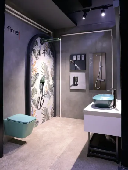 This tropical-themed bathroom display combines a leaf-patterned accent wall with teal sanitary ware for a fresh and vibrant look.