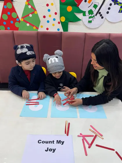 A teacher guides two students as they count with festive sticks. This small group interaction allows for personalized attention, ensuring each child grasps the concept at their own pace.