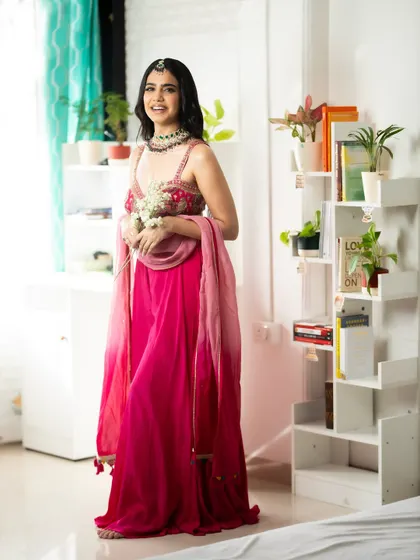 A full-length shot of the pink sharara set in a bright, indoor setting. This shows how the outfit looks in a home or studio environment.