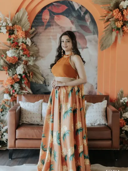 The client posing against a beautiful floral backdrop. Her soft, wavy hair complements the festive decor perfectly.