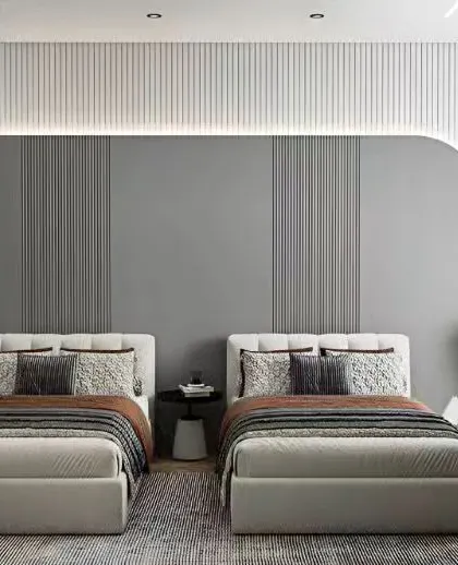 A contemporary bedroom with two single beds, featuring a textured grey and white accent wall with integrated backlighting. The design is clean, symmetrical, and perfect for a shared room.