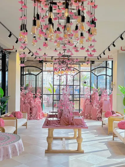 An elegant bridal shower bathed in blush pink. The space is illuminated by custom chandeliers dripping with pink flowers and Edison bulbs, creating a romantic and modern ambiance for the bride-to-be.