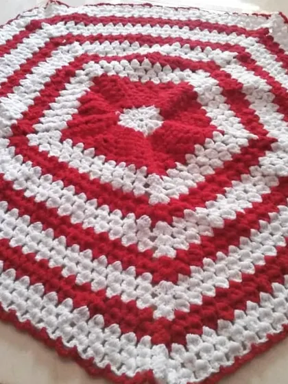 A hexagonal table mat with a simple, bold striped pattern in red and white.