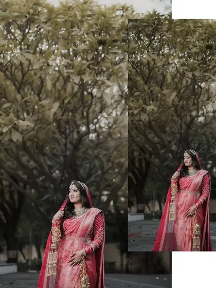 An artistic bridal portrait set against a natural backdrop. The bride stands gracefully, her red saree contrasting with the lush trees, creating a painterly effect.