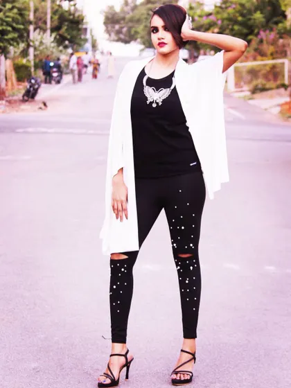 A full length view of an edgy, street style inspired look. The dramatic makeup with a smokey eye and red lip pairs perfectly with the modern black and white outfit, showing versatility for different types of events.