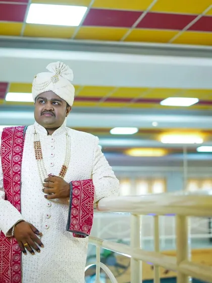 The groom in his stately white sherwani and pheta, posing elegantly at the wedding venue.