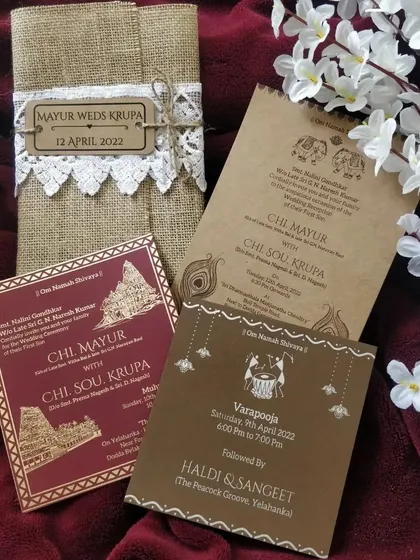 The full handmade wedding invitation suite. It includes separate inserts for different events like the Varapooja, Haldi, and Sangeet, all unified by a consistent design language and wrapped in a beautiful jute and lace folder.