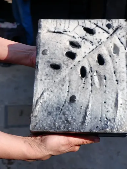 A stunning Raku-fired wall piece made by a workshop participant. The white crackle glaze and pierced holes create a dramatic effect against the carbon-blackened clay.