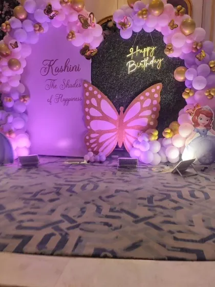 Another angle of the enchanting butterfly and princess stage decoration. The purple lighting enhances the magical feel of the balloon arch, butterfly cutout, and Sofia the First characters.