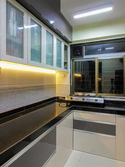 A practical kitchen with a black granite countertop and a mix of grey and white cabinets. The frosted glass on the upper cabinets adds a touch of lightness to the design.