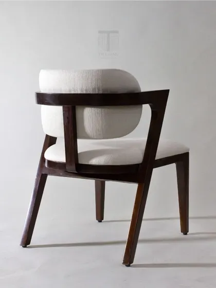 A back view of the armchair, showcasing the unique construction and the beautiful contrast between the dark wood and the light upholstery.