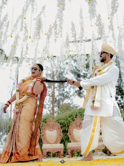 A candid, fun-filled moment where the groom playfully pulls on the bride's braid during their ceremony.