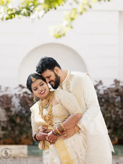 A joyful portrait of the couple in their white and gold wedding attire, sharing a warm embrace.