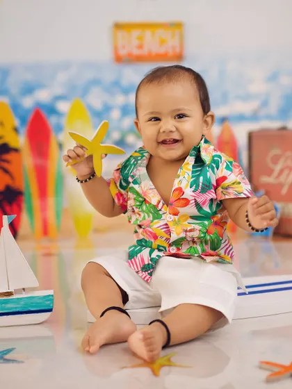 This little one is holding a starfish and smiling, perfectly capturing the joy of a summer-themed photoshoot.