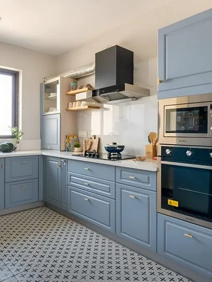 This U-shaped kitchen features a classic look with powder-blue shaker cabinets and a patterned tile floor. I integrated the oven and microwave into a tall unit to save counter space.