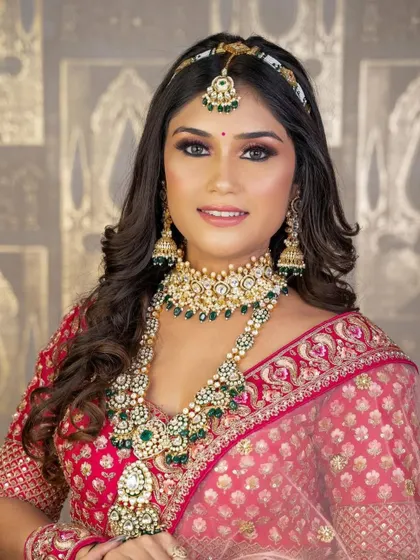 This layered green kundan set, complete with a choker, long necklace, and sheeshpatti, looks incredible against the bride's pink lehenga.