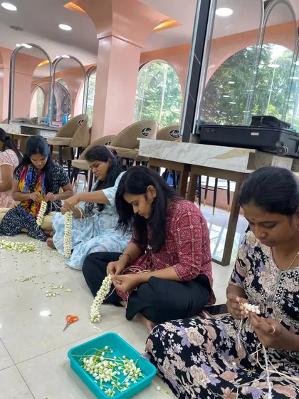 Students practicing jasmine garland techniques, a staple for South Indian brides.