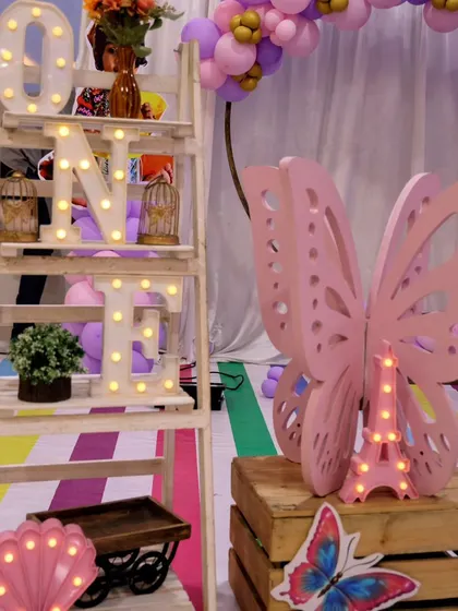 A detailed shot of the light-up 'ONE' shelf and butterfly prop from a fairy-themed party. These little details add so much magic to the setup.