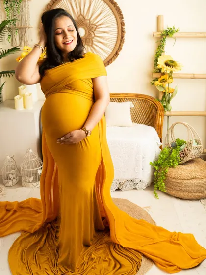 A confident standing pose in a vibrant yellow gown. This shot showcases the full length of the dress and the beautiful baby bump.