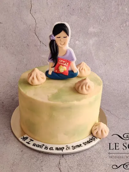 A cake for someone who just wants a nap and some snacks. This 1 kg Honey Pistachio cake is decorated with a meditating figurine, a bag of chips, and fondant momos.