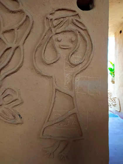 This charming mud relief depicts a woman carrying a pot, a scene from daily village life. By incorporating such art, the buildings themselves become a narrative of the community's identity and traditions.