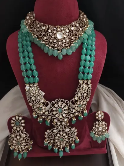This grand Victorian set in a deep emerald green is designed for a bride. The intricate workmanship on the choker and layered necklace makes it a true statement piece.