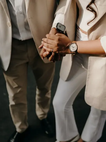 A close-up on their intertwined hands and matching watches. This detail shot symbolizes their connection and time spent together.