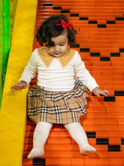 This stylish toddler is enjoying a gentle ride down our colorful roller slide, designed for safe fun.