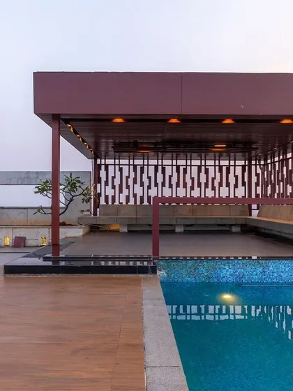 The rooftop includes a semi-covered gazebo for shaded seating next to the pool. The perforated metal screens provide privacy and create interesting light patterns, adding to the modern aesthetic.