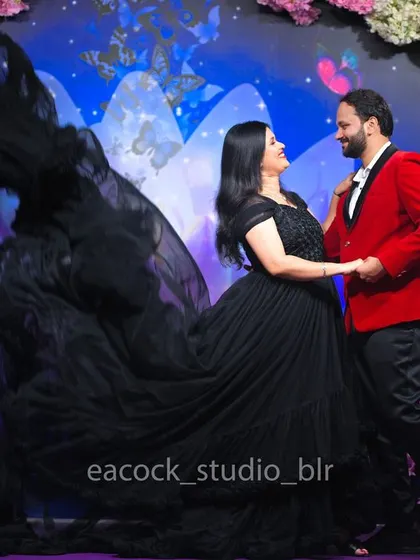 A dancing pose from a pre-wedding studio shoot, showing the beautiful movement of the black trail gown and the couple's coordinated, elegant outfits.